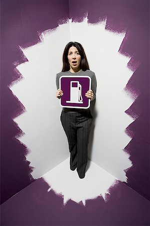 position afraid - Portrait of a mid adult woman holding a fuel pump signboard Stock Photo - Premium Royalty-Free, Code: 640-01353332