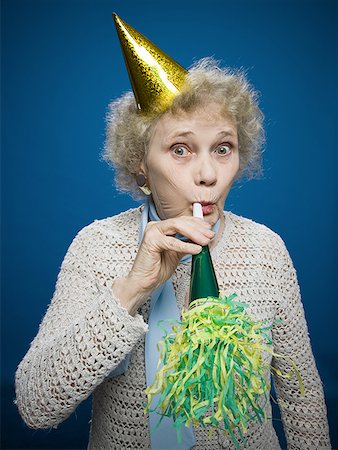 senior birthday - Older woman with noisemaker and party hat Stock Photo - Premium Royalty-Free, Code: 640-01353345