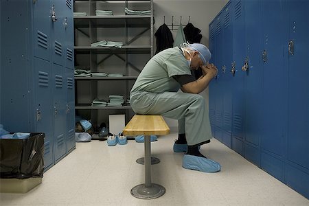 Profile of a surgeon sitting on a bench with his head in his hands Stock Photo - Premium Royalty-Free, Code: 640-01353356