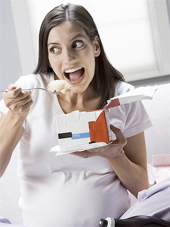 eating ice cream on couch - Close-up of a pregnant woman sitting on a couch eating ice- cream Stock Photo - Premium Royalty-Free, Code: 640-01353432