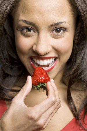 Portrait of a young woman eating a strawberry Stock Photo - Premium Royalty-Free, Code: 640-01353511