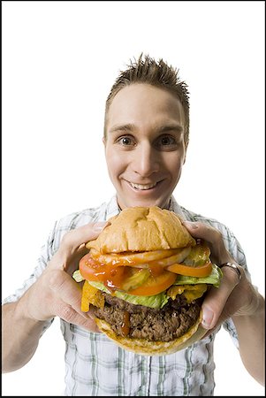 starve - Portrait of a young man holding a hamburger and smiling Stock Photo - Premium Royalty-Free, Code: 640-01353785