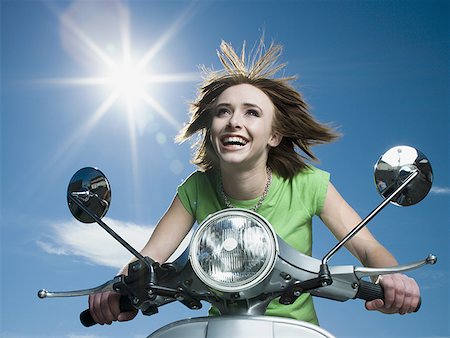 Low angle view of a teenage girl riding a scooter Stock Photo - Premium Royalty-Free, Code: 640-01353963