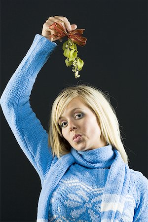 Portrait d'une jeune femme tenant le GUI au-dessus de sa tête et plisser les lèvres Photographie de stock - Premium Libres de Droits, Code: 640-01364541