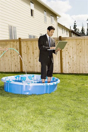 simsearch:640-01355157,k - Homme d'affaires à l'aide d'un ordinateur portable, debout dans une piscine pour enfants Photographie de stock - Premium Libres de Droits, Code: 640-01364816