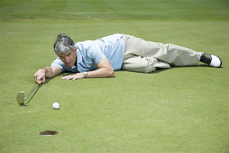 simsearch:640-02768050,k - Man lying near a golf hole Foto de stock - Royalty Free Premium, Número: 640-01364884