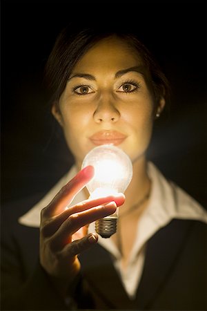 electric abstract - Portrait of a younger businesswoman with illuminated light bulb Stock Photo - Premium Royalty-Free, Code: 640-01364893