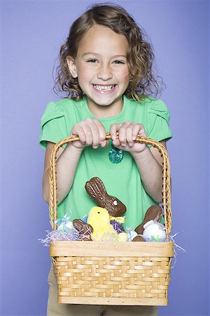 Portrait of a girl holding Easter bunnies and Easter eggs in a wicker basket Stock Photo - Premium Royalty-Free, Code: 640-01365127