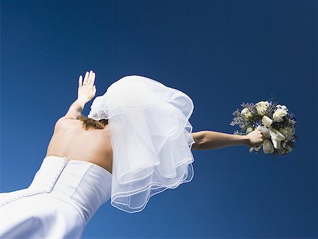 simsearch:640-01349457,k - Low angle view of a bride holding a bouquet of flowers with her arms raised Foto de stock - Sin royalties Premium, Código: 640-01365151
