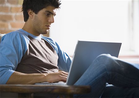 Young man working on a laptop Stock Photo - Premium Royalty-Free, Code: 640-01365194