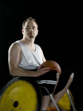 Close-up of a young man sitting in a wheelchair holding a basketball Stock Photo - Premium Royalty-Free, Code: 640-01365297