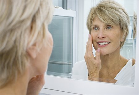 simsearch:640-01358246,k - Portrait of a mature woman applying moisturizer on her face Stock Photo - Premium Royalty-Free, Code: 640-01365525