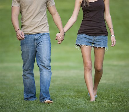 Close-up of a young man and woman holding hands and walking in a park Stock Photo - Premium Royalty-Free, Code: 640-01365639