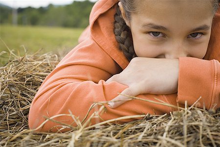 Portrait of a girl leaning over a haystack Stock Photo - Premium Royalty-Free, Code: 640-01365714