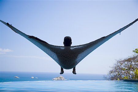 Rear view of a young man relaxing in a hammock Stock Photo - Premium Royalty-Free, Code: 640-01365820