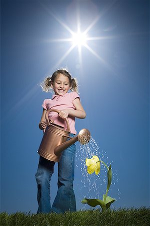 Low angle view of a girl watering a plant Stock Photo - Premium Royalty-Free, Code: 640-01365852