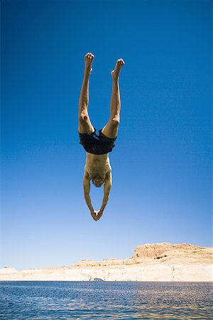 simsearch:640-01366168,k - Low angle view of a young man jumping in water Foto de stock - Royalty Free Premium, Número: 640-01366108