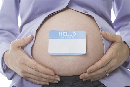 Mid section view of a pregnant woman with a name tag on her abdomen Foto de stock - Sin royalties Premium, Código: 640-01366187