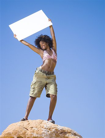 simsearch:640-01366289,k - Low angle view of a young woman holding a blank sign Fotografie stock - Premium Royalty-Free, Codice: 640-01366284