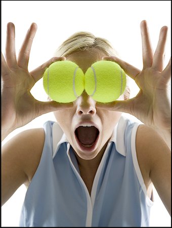 Close-up of a young woman holding tennis balls in front of her eyes Stock Photo - Premium Royalty-Free, Code: 640-01366391