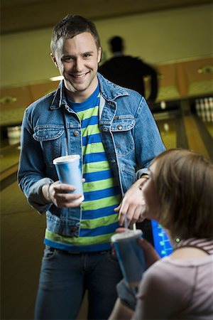 Portrait of a young man holding a glass of cola and looking at a teenage girl Stock Photo - Premium Royalty-Free, Code: 640-01366557