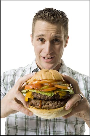 simsearch:640-01356052,k - Portrait d'un jeune homme tenant un hamburger Photographie de stock - Premium Libres de Droits, Code: 640-01366560