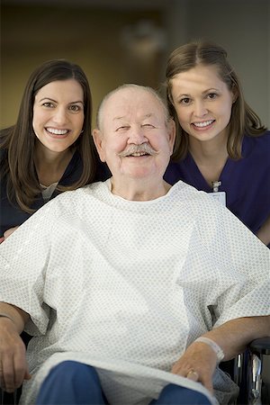 Portrait of two female nurses helping a male patient sitting on a wheel chair Stock Photo - Premium Royalty-Free, Code: 640-01366618