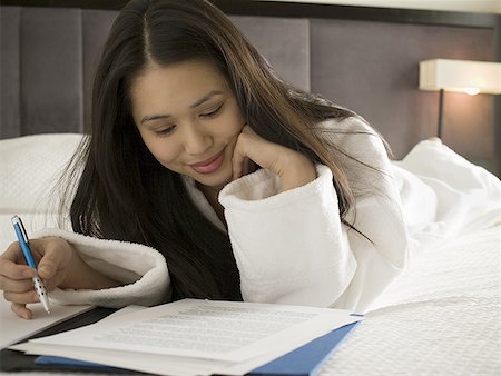 Close-up of a young woman reading sheets of paper holding a pen Fotografie stock - Premium Royalty-Free, Codice: 640-01366625