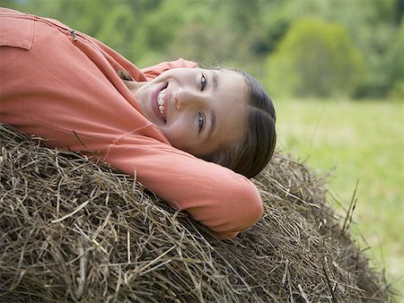 Portrait d'une jeune fille allongée sur une balle de foin Photographie de stock - Premium Libres de Droits, Code: 640-01360190