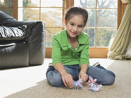 dark haired young girl on a horse - Portrait of a girl sitting on the floor and playing with toys Stock Photo - Premium Royalty-Free, Code: 640-01360381