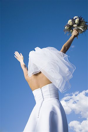 simsearch:640-01362473,k - Low angle view of a bride holding a bouquet of flowers with her arms raised Stock Photo - Premium Royalty-Free, Code: 640-01360518