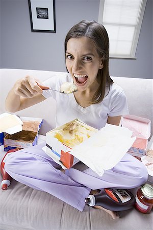 eating ice cream on couch - Young woman sitting on a couch eating ice-cream Stock Photo - Premium Royalty-Free, Code: 640-01360618