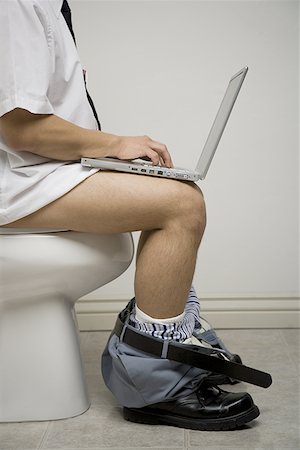 defecation - Mid section view of a young man sitting on the toilet seat using a laptop Stock Photo - Premium Royalty-Free, Code: 640-01360633