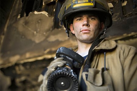 firefighter close - Low angle view of a firefighter holding a fire hose Stock Photo - Premium Royalty-Free, Code: 640-01360915