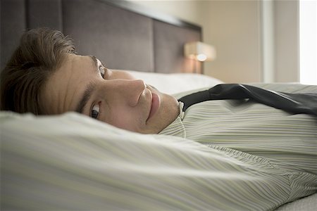 Portrait of a businessman lying on the bed Fotografie stock - Premium Royalty-Free, Codice: 640-01360944