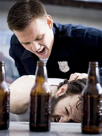 simsearch:640-01355636,k - Police officer arresting man lying down with beer bottles Fotografie stock - Premium Royalty-Free, Codice: 640-01360999