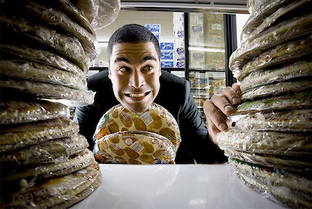 person standing and eating pizza - Homme tenant des pizzas à l'épicerie Photographie de stock - Premium Libres de Droits, Code: 640-01361274