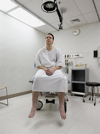 Patient sitting in a hospital wearing an examination gown Stock Photo - Premium Royalty-Free, Code: 640-01361479