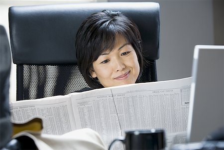 Woman reading financial pages of newspaper Stock Photo - Premium Royalty-Free, Code: 640-01361691