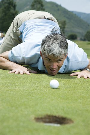 simsearch:640-01362317,k - Man kneeling near a golf hole Foto de stock - Sin royalties Premium, Código: 640-01361739