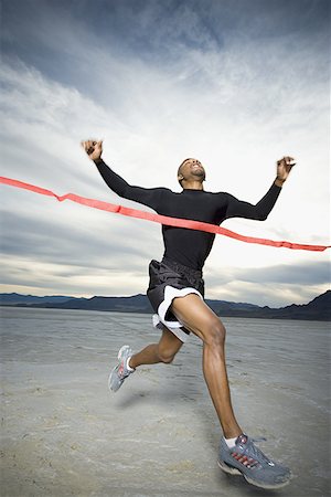running shot - Young man crossing the finish line with his arms raised Stock Photo - Premium Royalty-Free, Code: 640-01361799
