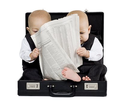 Twin boys sitting in a briefcase with newspaper Stock Photo - Premium Royalty-Free, Code: 640-01361892