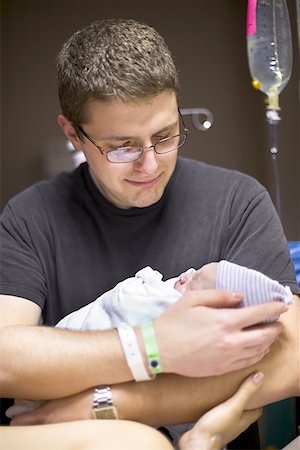 father holding a baby in his hands - Father carrying his newborn baby girl in a hospital ward Stock Photo - Premium Royalty-Free, Code: 640-01362006