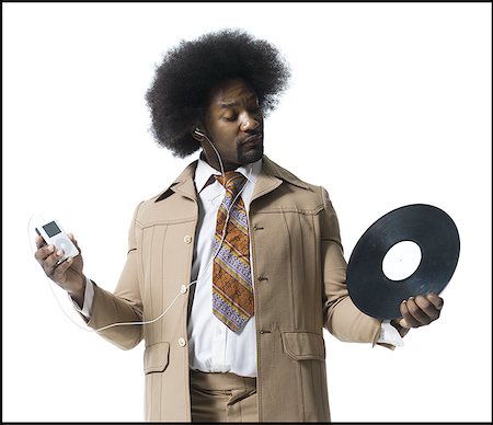 Man with an afro in beige suit listening to MP3 player Stock Photo - Premium Royalty-Free, Code: 640-01362046
