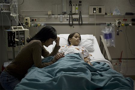 person in hospital bed overhead - High angle view of a girl lying on a hospital bed with her mother holding her hand beside her Stock Photo - Premium Royalty-Free, Code: 640-01362568