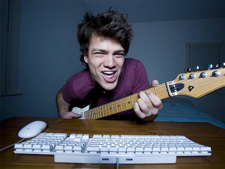 Man at keyboard playing guitar and singing Stock Photo - Premium Royalty-Free, Code: 640-01362659