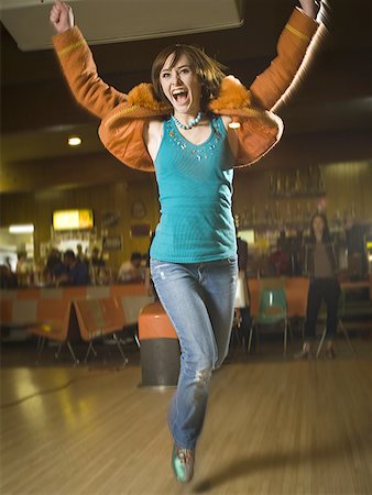 Teenage girl jumping in excitement in a bowling alley Stock Photo - Premium Royalty-Free, Code: 640-01362668