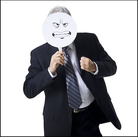 Businessman holding a determined face mask Stock Photo - Premium Royalty-Free, Code: 640-01362660