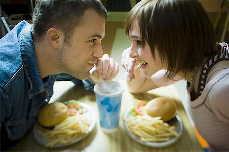 fast food restaurant - High angle view of a young man and a teenage girl looking at each other and drinking Stock Photo - Premium Royalty-Free, Code: 640-01363108