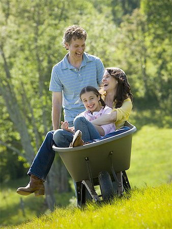 Man pushing his daughter and his wife in a wheelbarrow Stock Photo - Premium Royalty-Free, Code: 640-01363162